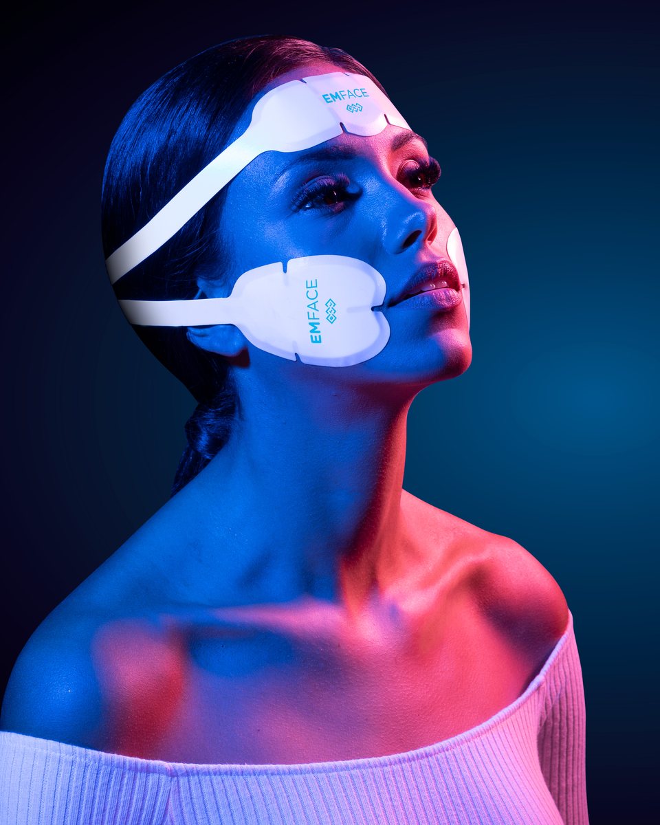 Patient relaxing during an EMFACE session with forehead and cheek applicators applied